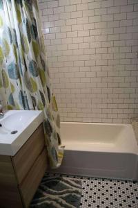 een badkamer met een bad, een wastafel en een douchegordijn bij Sunnyside Up Apartment in Denver