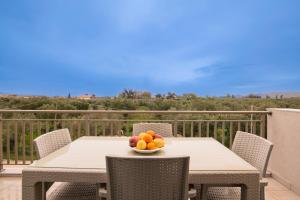 a table with a bowl of fruit on a balcony at Happiness Apartment in Laganas