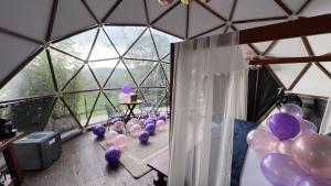 a room with purple balloons and a woman sitting in a tent at Casa Quincha Glamping in San Francisco