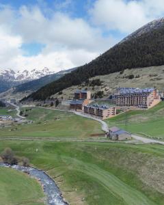 a hotel on a hill with a river and mountains at Apartamento Luxury en Bordes d'Envalira, Andorra in Soldeu