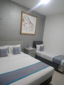 um quarto de hotel com duas camas e uma foto na parede em Smart Tlogomas Syariah em Malang