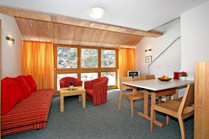 a living room with a red couch and a table at Ferienwohnungen Broser in Obergurgl