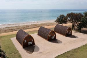 três casas rústicas de vime estão sentadas na praia em Bellarine Bayside Portarlington em Portarlington