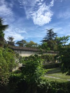 a stone building with trees and a blue sky at DameChouette in Pujols