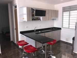 a kitchen with a black counter and red stools at Acogedor apartamento en Girardot: Aqualina Orange in Girardot