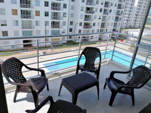 drie stoelen en een tafel op een balkon met een zwembad bij Acogedor apartamento en Girardot: Aqualina Orange in Girardot