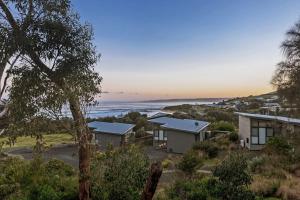 a group of houses on a hill with the ocean at Skenes Beach House Stunning Ocean Views Amongst A Natural Bush Setting in Apollo Bay