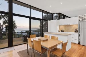 a kitchen and dining room with a table and chairs at Skenes Beach House Stunning Ocean Views Amongst A Natural Bush Setting in Apollo Bay