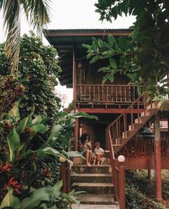 two children sitting on the stairs of a house at Baan Loylom Farmstay in Amphawa