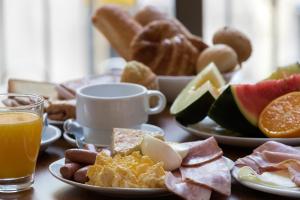 - une table avec des assiettes de produits pour le petit-déjeuner et du jus d'orange dans l'établissement Cuatro Naciones, à Barcelone