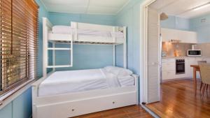 a bedroom with two bunk beds and a kitchen at Happy Ours - Patonga Beach in Patonga