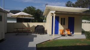 a small house with a picnic table and an umbrella at Happy Ours - Patonga Beach in Patonga
