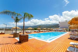 a swimming pool with chairs and umbrellas on a deck at Triton Hotel in Malia