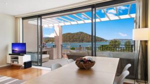 a living room with a table and a view of the ocean at Sea View - Ettalong Beach in Ettalong Beach