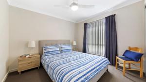 a bedroom with a bed and a chair and a window at Ocean Sounds - Umina Beach in Umina