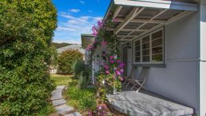 Lazy Days Seaside Cottage - Umina Beach في أومينا: منزل به زهور على جانبه