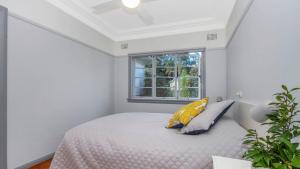 Lazy Days Seaside Cottage - Umina Beach في أومينا: غرفة نوم بسرير ومخدتين ونافذة