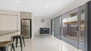 una cocina con nevera y algunas sillas. en Avani - Modern & Tranquil - Wifi, en Booker Bay