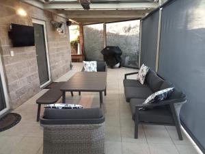 patio con sofás, mesa y TV en Riesling Trail & Clare Valley Cottages en Clare
