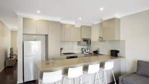 a kitchen with white cabinets and a bar with white stools at Beachbound - Booker Bay Wifi in Booker Bay