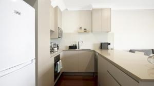 a kitchen with white cabinets and a sink at Beachbound - Booker Bay Wifi in Booker Bay
