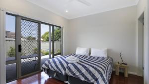 a white bedroom with a bed and a balcony at Beachbound - Booker Bay Wifi in Booker Bay +10 photos