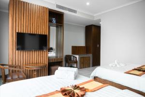 um quarto de hotel com duas camas e uma televisão de ecrã plano em The ONRA Hotel em Phnom Penh