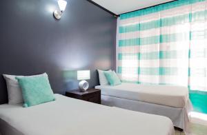1 dormitorio con 2 camas y ventana en Sweet Kensville @ New Kingston en Kingston