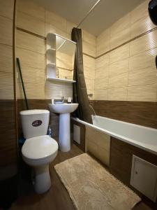 a bathroom with a toilet and a sink and a tub at Квартира на Тулебаева in Almaty