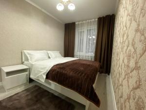 a bedroom with a large bed with a window at Квартира на Тулебаева in Almaty