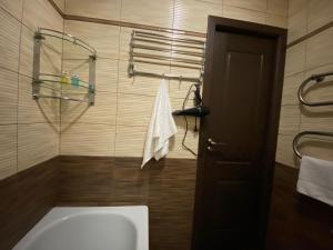 a bathroom with a tub and a door and a towel at Квартира на Тулебаева in Almaty