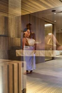 Una donna sta in piedi in una stanza con uno specchio di Executive Spa Hotel a Fiorano Modenese