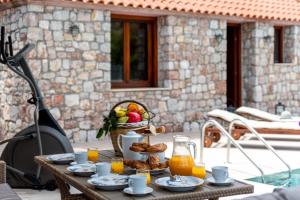 uma mesa com comida e uma cesta de frutas e sumo de laranja em Filerolia Stone House em Pastida