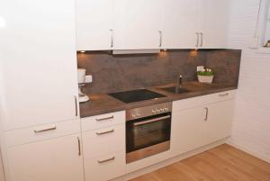 a white kitchen with a sink and a stove at Blockhaus mit W LAN sehr strandnah in Damp