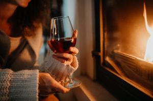 Eine Frau, die vor einem Kamin ein Glas Wein hält. in der Unterkunft Libling Podkrovný in Banská Štiavnica + 15 Fotos