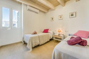 two beds in a white room with a window at Els Arbocers 131-2 in Cala Blanca