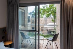 a room with a balcony with two chairs and a table at Urbanic Hotel in Jerusalem