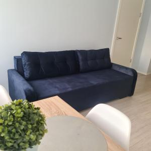 - un canapé bleu dans le salon avec une table dans l'établissement Alejas Lux Apartment, à Liepāja