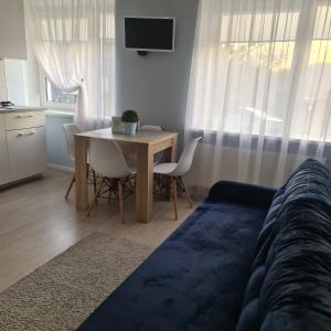 een woonkamer met een tafel met stoelen en een televisie bij Alejas Lux Apartment in Liepāja