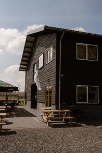 ein schwarzes Gebäude mit Picknicktischen davor in der Unterkunft De la Rue Vakantiesuites in Sleeuwijk