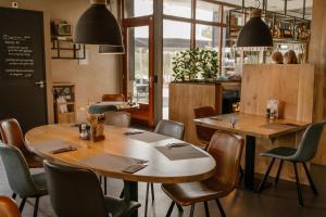 a restaurant with wooden tables and chairs and a chalkboard at De la Rue Vakantiesuites in Sleeuwijk