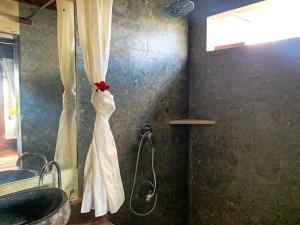 a bathroom with a shower with a white shower curtain at Canggu Spirit Guest House in Canggu