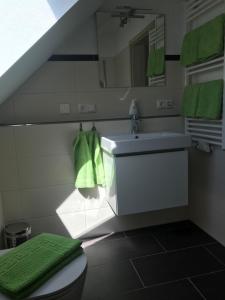 a bathroom with a sink and a toilet and green towels at Sonniges 4 **** DG-Apartment mit Aufzug+Seeblick in Ramsberg +45 photos