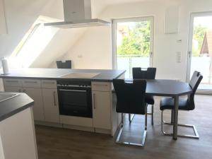 a kitchen with a table and a stove and chairs at Sonniges 4 **** DG-Apartment mit Aufzug+Seeblick in Ramsberg