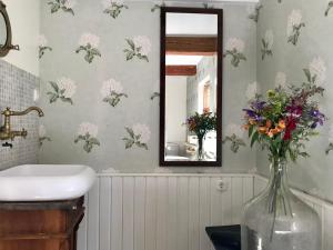 ein Badezimmer mit Spiegel und einer Vase mit Blumen in der Unterkunft Sea Breeze Cottage in Eisma