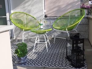 um pátio com 2 cadeiras verdes e uma mesa em Ferienwohnung im Fischerhaus em Nonnenhorn