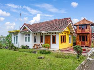een klein geel-wit huis met een tuin bij SPOT ON 91107 Villa Galaxy Resort in Cikundul