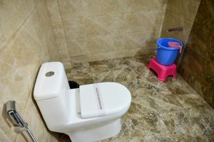 a bathroom with a white toilet and a blue bucket at The Fern Villas Nainital By Beyond Stay in Nainital