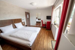 a bedroom with a white bed and a desk and a window at Garni Hotel Henn in Simmerath
