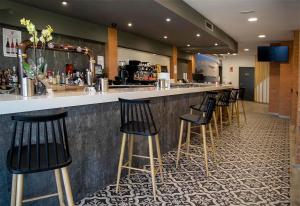a bar with a row of black bar stools at Hostal Restaurante Cuatro Caminos in Cubillos del Sil